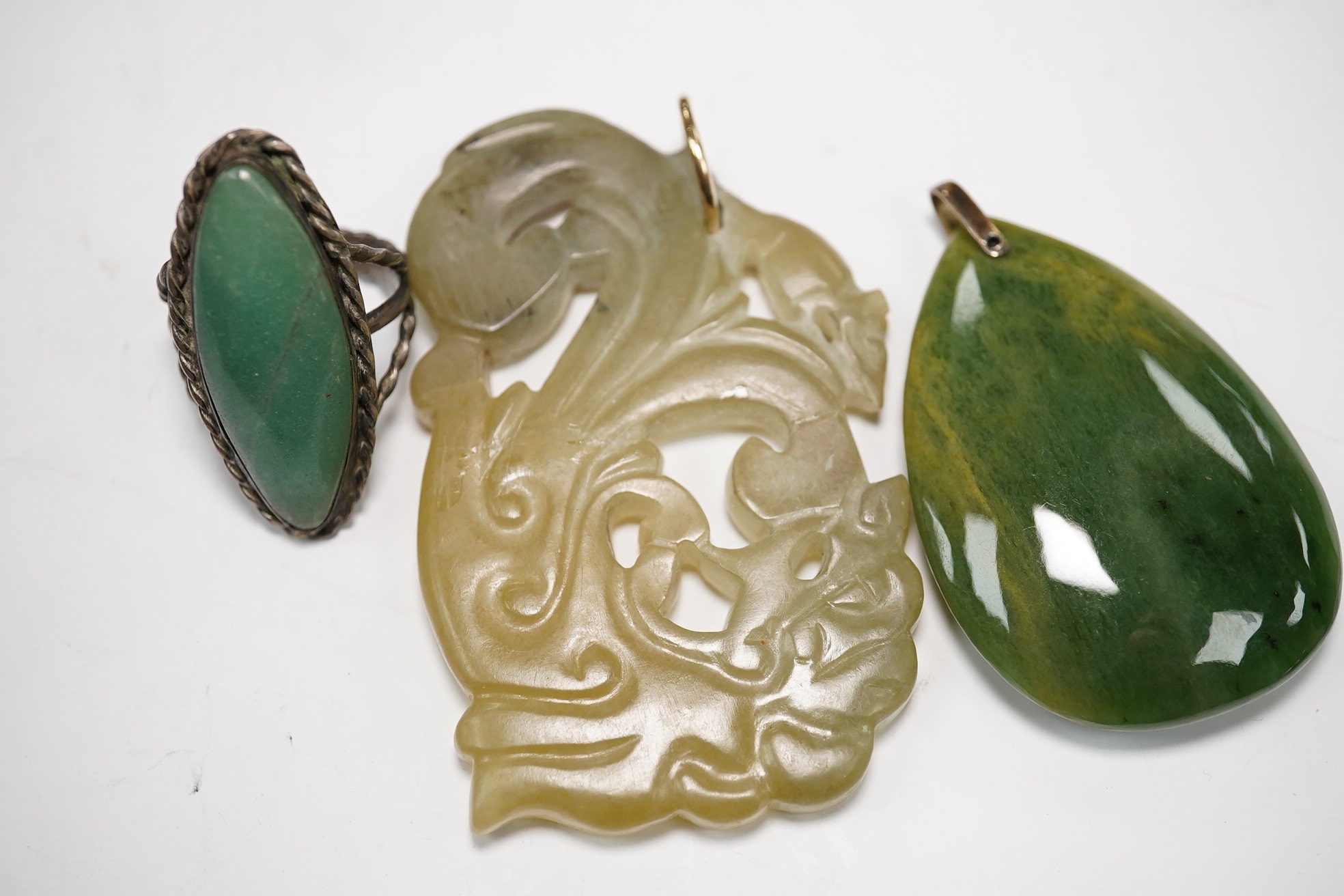 Two jade pendants including a carved example and a jade marquise ring, largest 6.5cm wide. Condition - fair to good